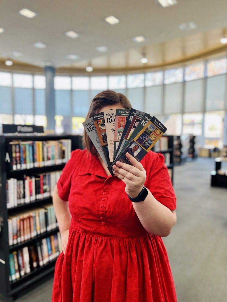 Person in red dress holding bookmarks in library