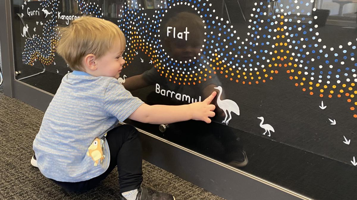 child looking at Kangaroo Flat First Nations artwork on counter
